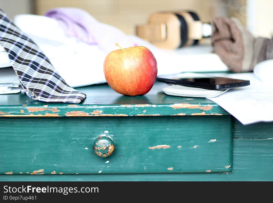 An apple on a desk with paperwork and men's clothes. An apple on a desk with paperwork and men's clothes.