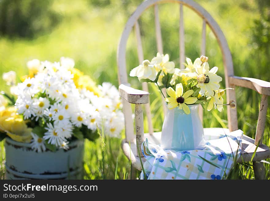 A bunch of daisies in a jar next to a chair in the garden. A bunch of daisies in a jar next to a chair in the garden.