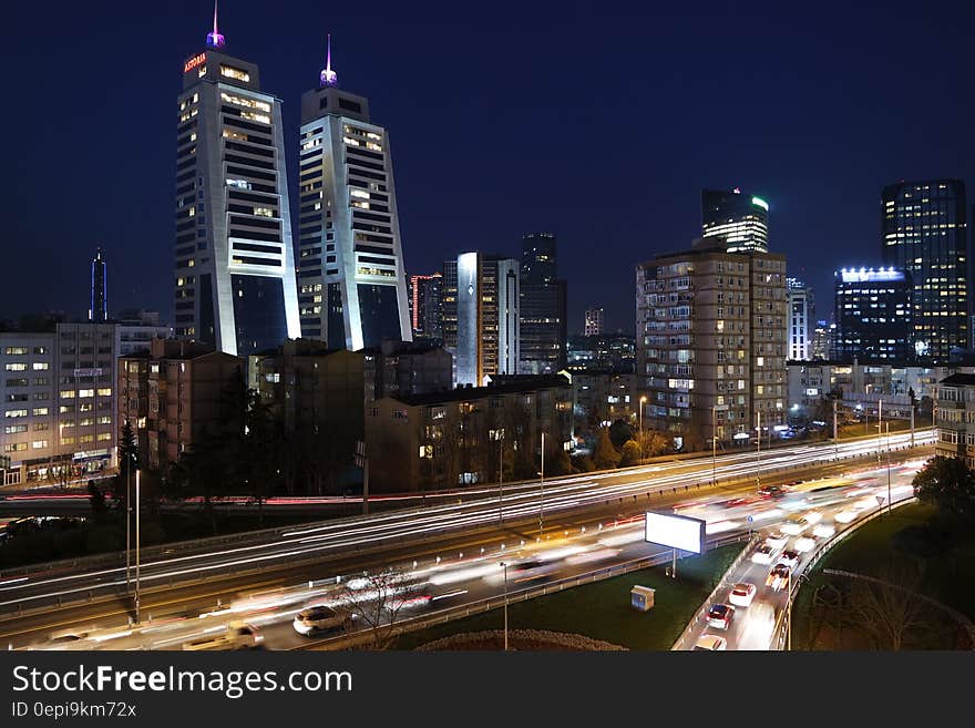 Heavy traffic moving on the highway traveling north and south through city with illuminated skyscrapers and dark blue sky. Heavy traffic moving on the highway traveling north and south through city with illuminated skyscrapers and dark blue sky.