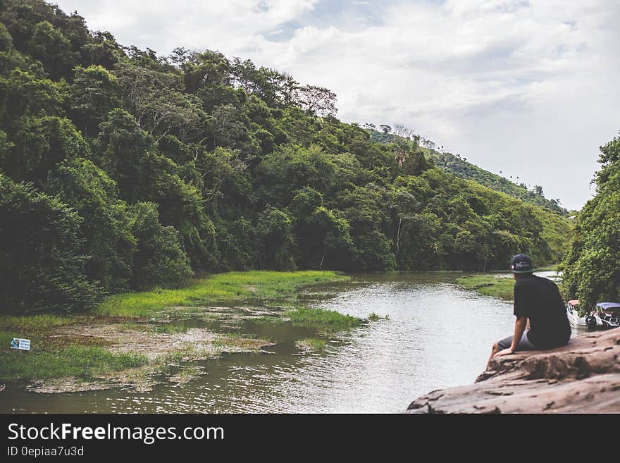 A man sitting at the rocks watching a river. A man sitting at the rocks watching a river.