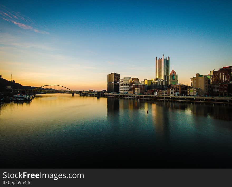 City skyline with a bridge and a small river harbor at sunset. City skyline with a bridge and a small river harbor at sunset.