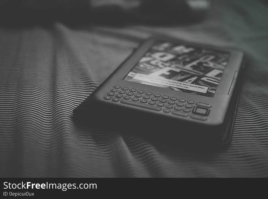 Close up of Kindle e-reader on bed in black and white. Close up of Kindle e-reader on bed in black and white.