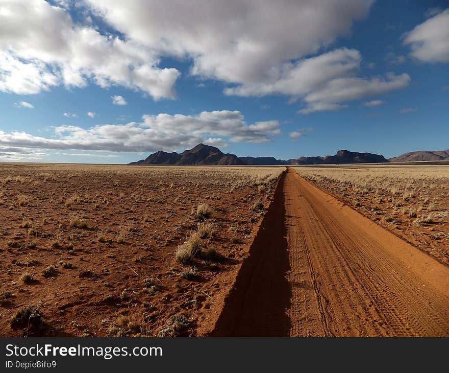 Brown Sandy Field Under Blue and White Cloudy Sky