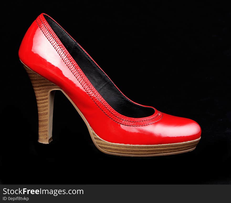 Bright red platform heel with wood sole on black background.