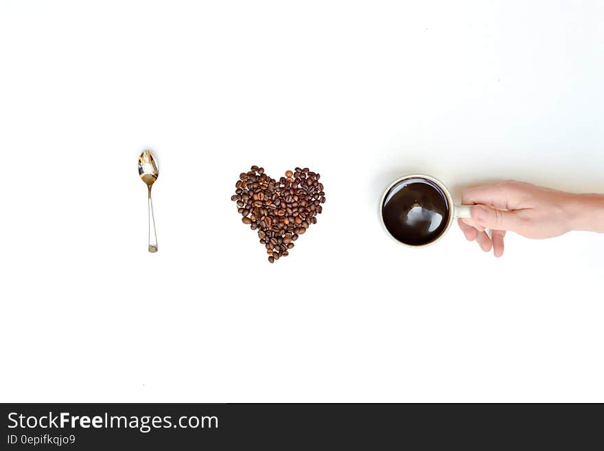 I love coffee spelled with spoon, coffee beans and hand holding coffee cup.