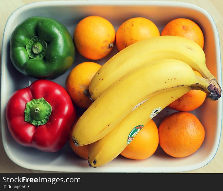 Plastic bowl with oranges, bananas, red and green bell peppers. Plastic bowl with oranges, bananas, red and green bell peppers.