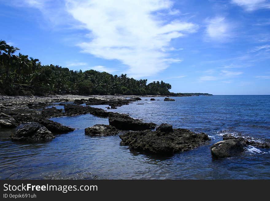 Large Rocks on Seashore Under White Cloudy Sky during Daytime