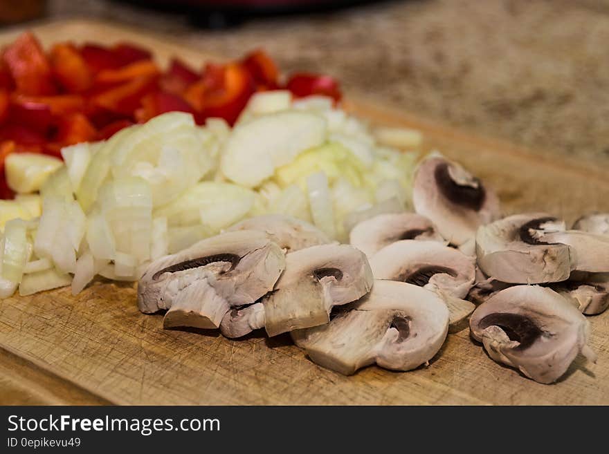 Close up of sliced mushrooms, onions and red peppers on wooden cutting board. Close up of sliced mushrooms, onions and red peppers on wooden cutting board.