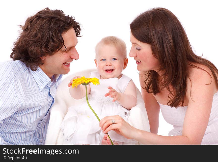 Man in White and Gray Stripe Button Up Long Sleeve Shirt Facing Baby in White Sleeveless Dress Beside Woman in White Strapless Dre