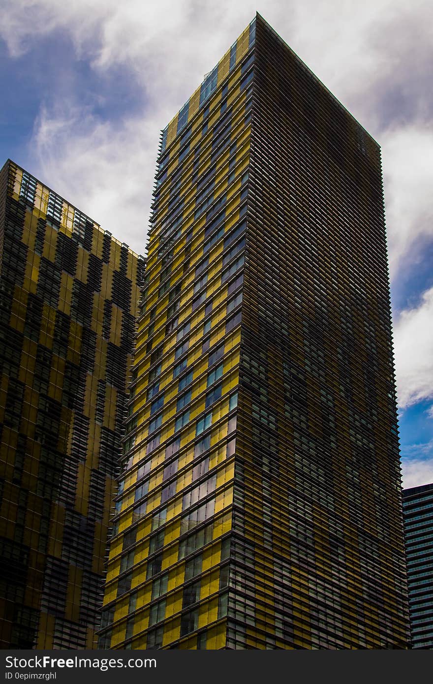 Yellow and Gray High Rise Buildings Under Blue and White Sunny Cloudy Sky