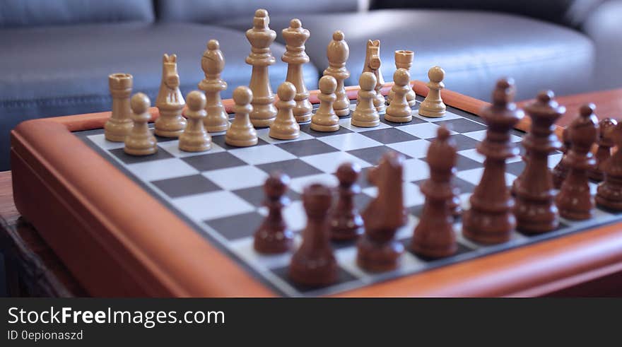 Wooden chess pieces on chessboard inside home. Wooden chess pieces on chessboard inside home.