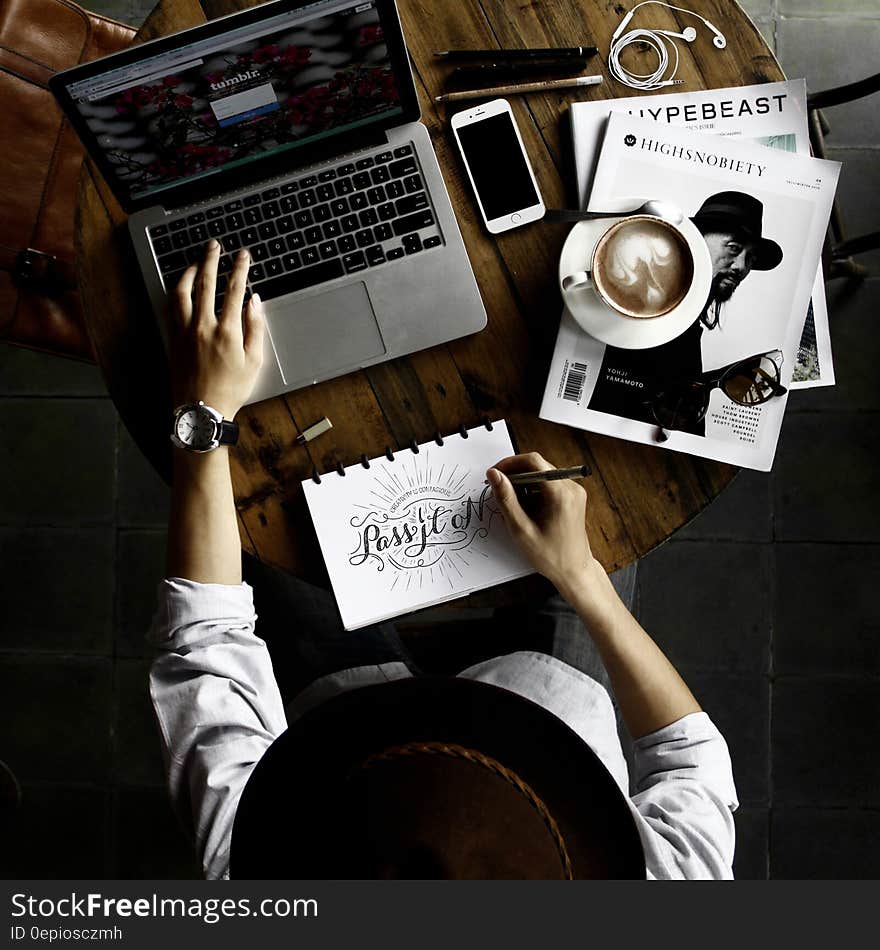 Overhead of calligraphy artists sketching on pad and using laptop computer on desktop. Overhead of calligraphy artists sketching on pad and using laptop computer on desktop.