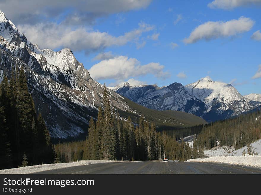 Empty alpine road through mountain peaks against blue skies on sunny day. Empty alpine road through mountain peaks against blue skies on sunny day.