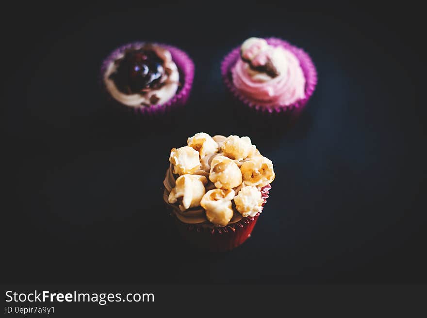 Yellow and Brown Cupcake Near Purple and White Cupcake