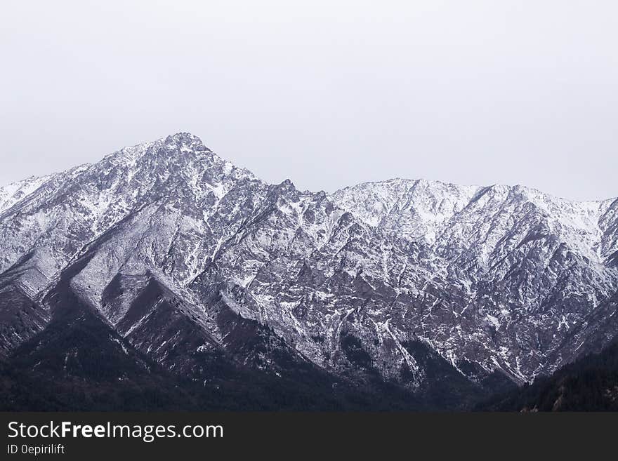 Snow covered mountain peaks against overcast skies in China. Snow covered mountain peaks against overcast skies in China.