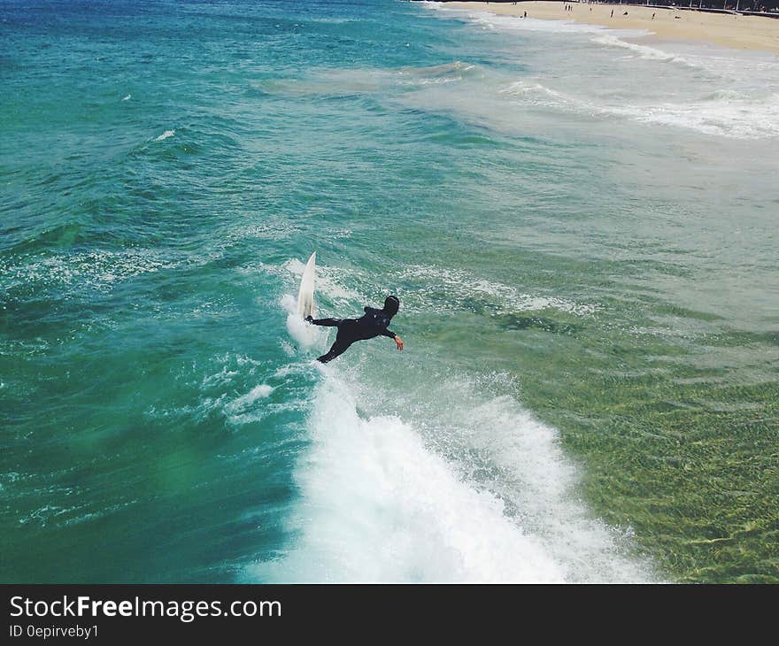 Surfer on waves along sandy shores on sunny day. Surfer on waves along sandy shores on sunny day.