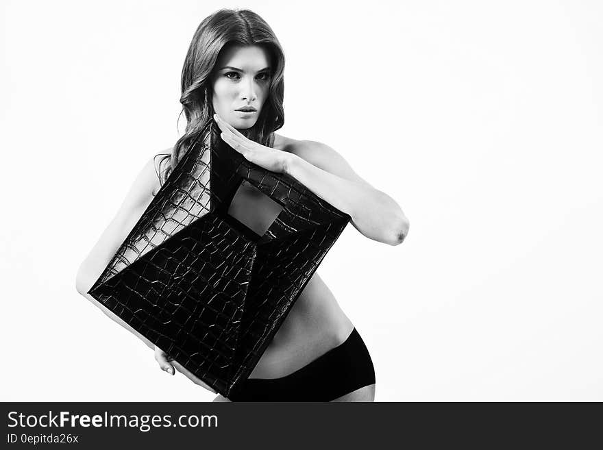 Greyscale Photography of Woman Holding Leather Square Covering Her Upper Body