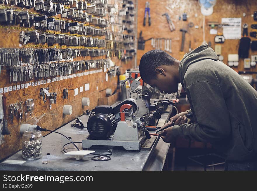 Man in Grey Hoodie Jacket Holding Black Metal Near White Socket Power Supply