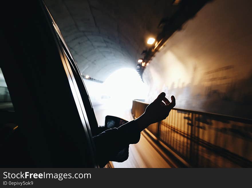 Hand outside car window traveling through sunny tunnel. Hand outside car window traveling through sunny tunnel.