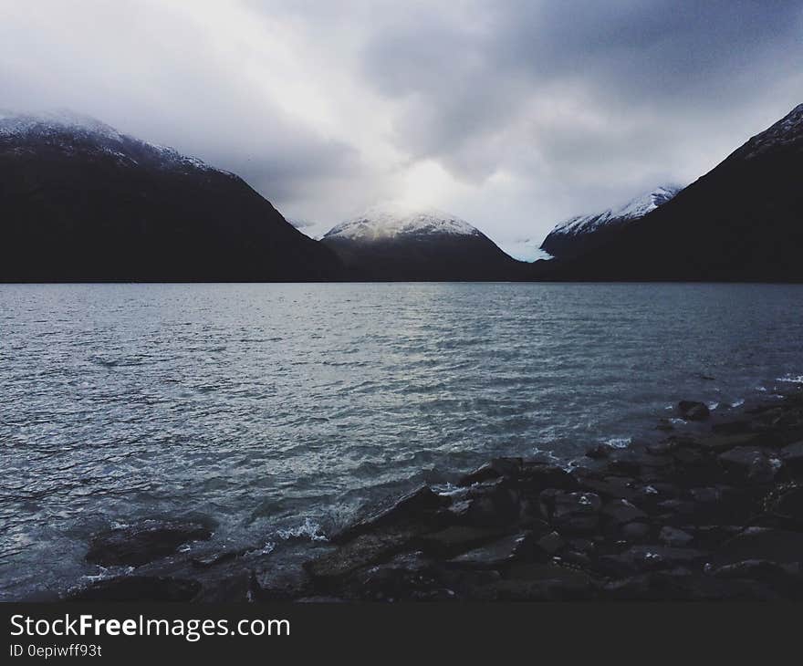 Grey cloudy skies over alpine lake on stormy day.