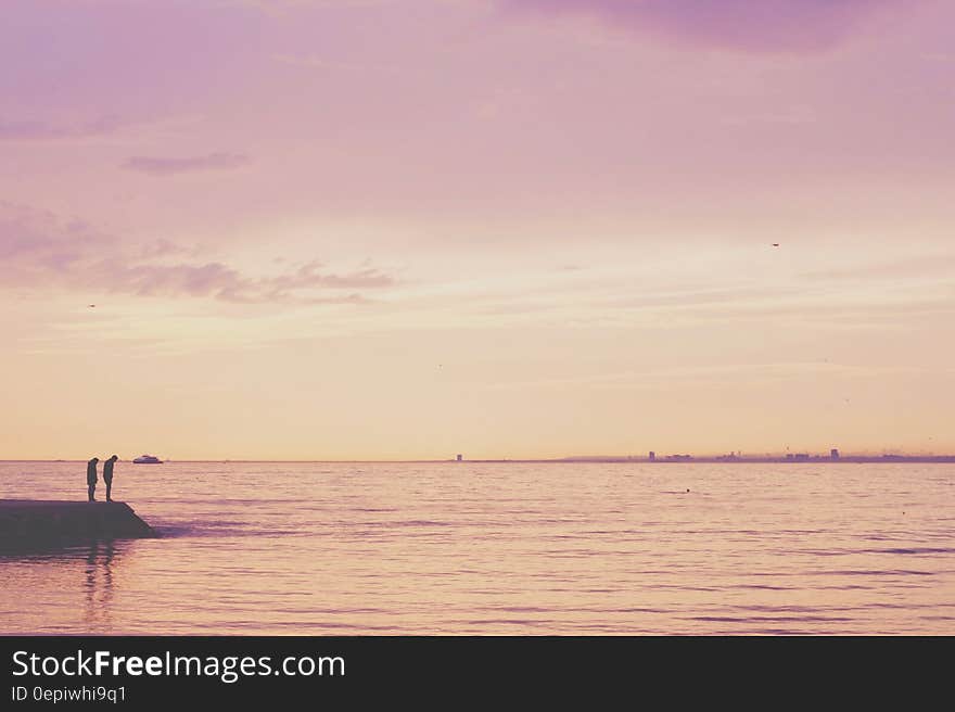 2 Person Standing on Shore Near Calm Sea