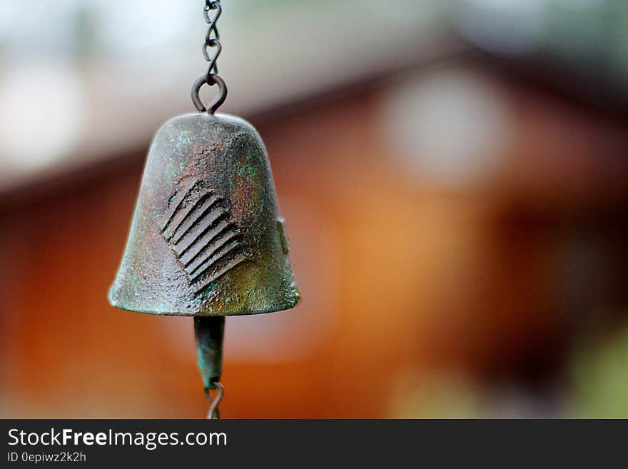 An old fashioned hanging metal bell on a blurred background. An old fashioned hanging metal bell on a blurred background.