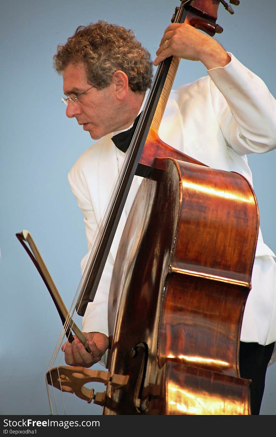 Man in tuxedo playing bass onstage during concert. Man in tuxedo playing bass onstage during concert.