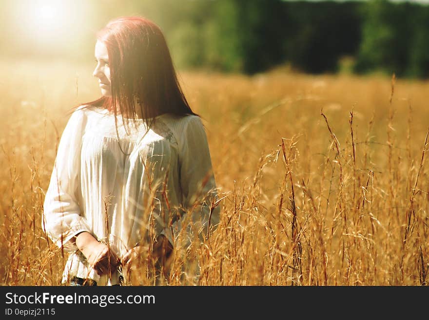 Woman Wearing White Long Sleeved Shirt Standing in Brown Grass Field