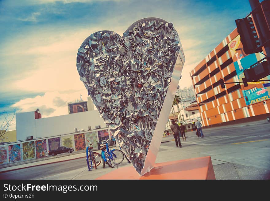 Solid heart shape standing on its pointed end, tall as a house and created as a piece of artistic sculpture, symbol of love, urban background. Solid heart shape standing on its pointed end, tall as a house and created as a piece of artistic sculpture, symbol of love, urban background.