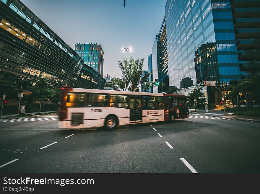 White Bus on Road Near in High Rise Building during Daytime