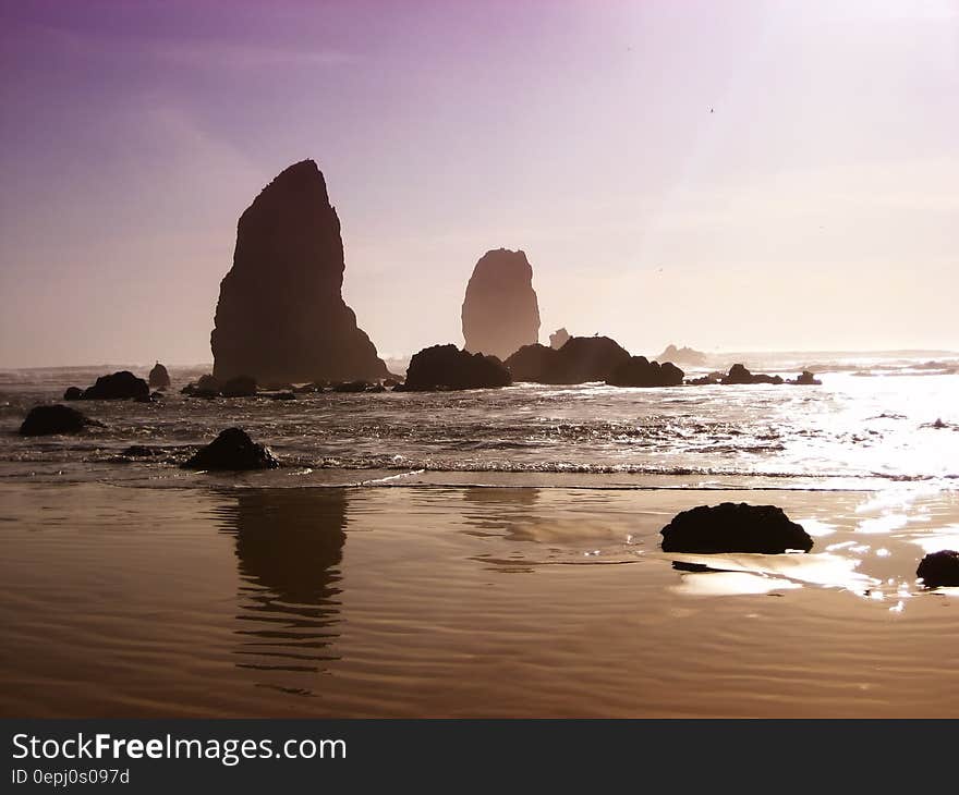 Rocky shores along sandy beach at sunset with purple skies. Rocky shores along sandy beach at sunset with purple skies.