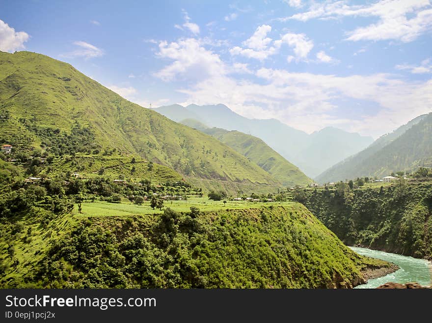 Green Valley With Wending River Under White Clouds and Blue Sky during Daytime