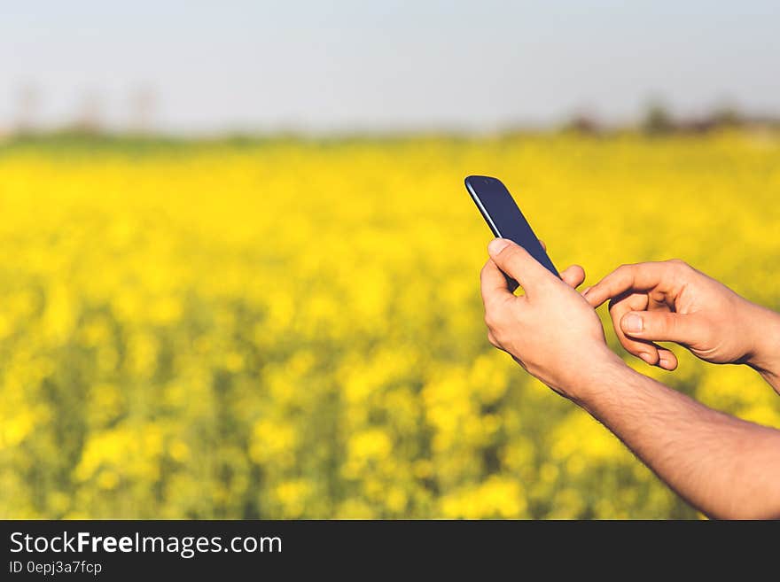 Smartphone Acer Jade S in the hands of a man on a background of yellow flowers