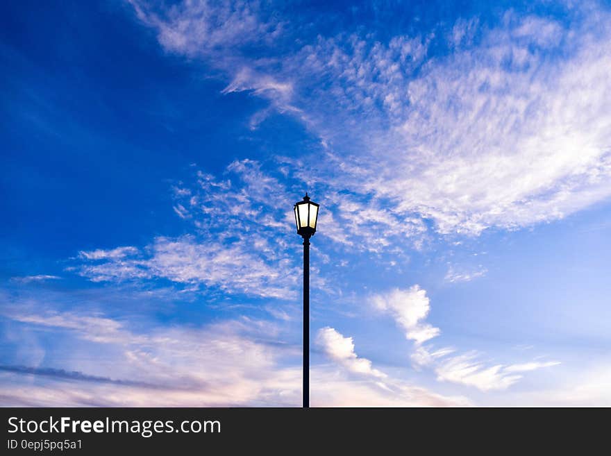 Streetlamp on post against blue skies with white clouds. Streetlamp on post against blue skies with white clouds.