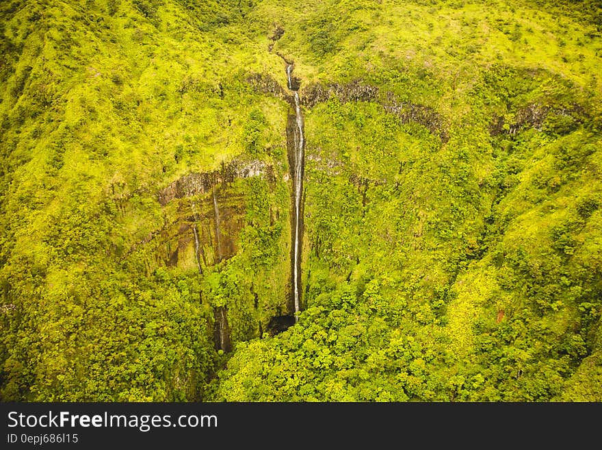 Aerial view over waterfall over green cliff. Aerial view over waterfall over green cliff.