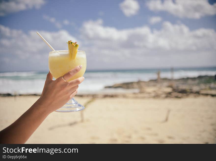 Hand holding fancy cocktail on sunny beach. Hand holding fancy cocktail on sunny beach.