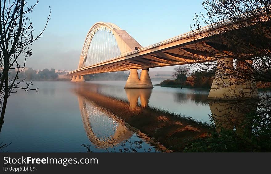 Grey Concrete Bridge Above Water Under Blue Sky