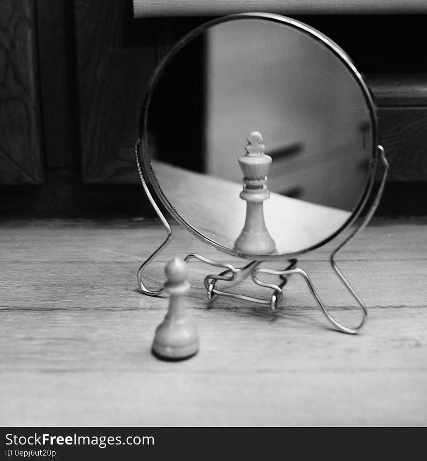 Grayscale Photo of Reversible Mirror in Front of Chess Piece