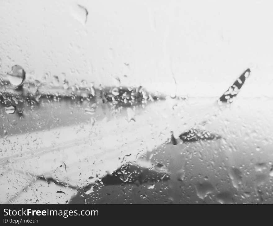 Airplane wing through rainy window in black and white.