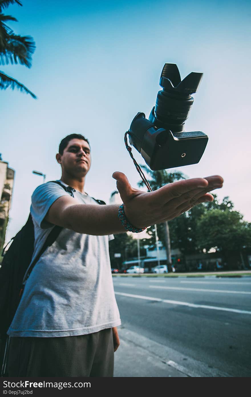 Man Throwing Black Camera in Air