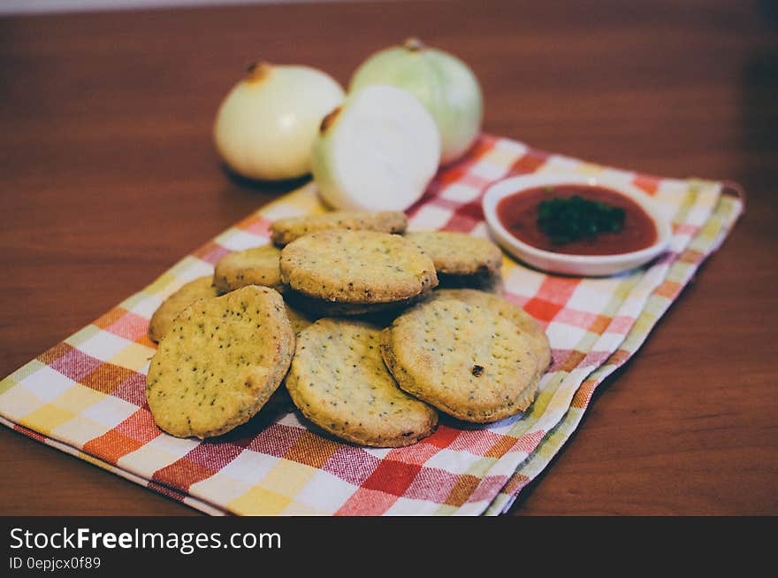 Baked Round Cookie Beside Red Sauce With Green Toppings