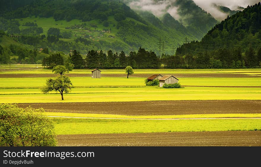 Brown House in the Middle of Green Field Grass Near Mountains