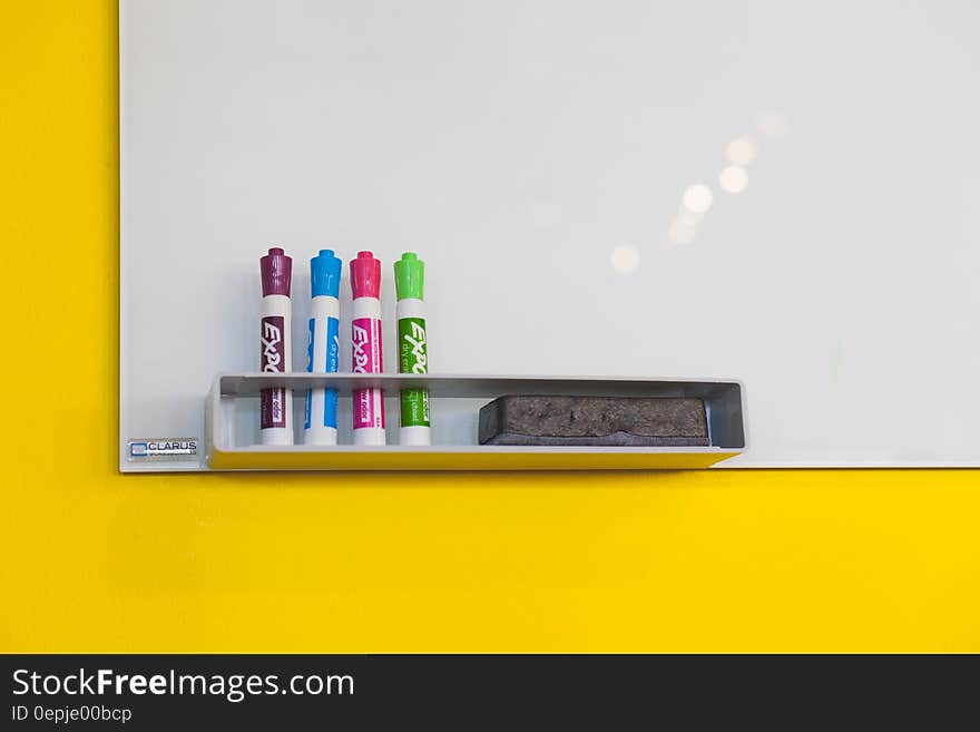 Colorful markers and eraser at whiteboard on yellow wall. Colorful markers and eraser at whiteboard on yellow wall.