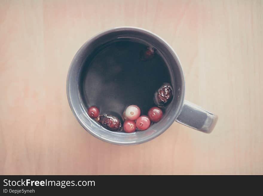 Overhead view of berries and tea in china mug on wooden tabletop. Overhead view of berries and tea in china mug on wooden tabletop.