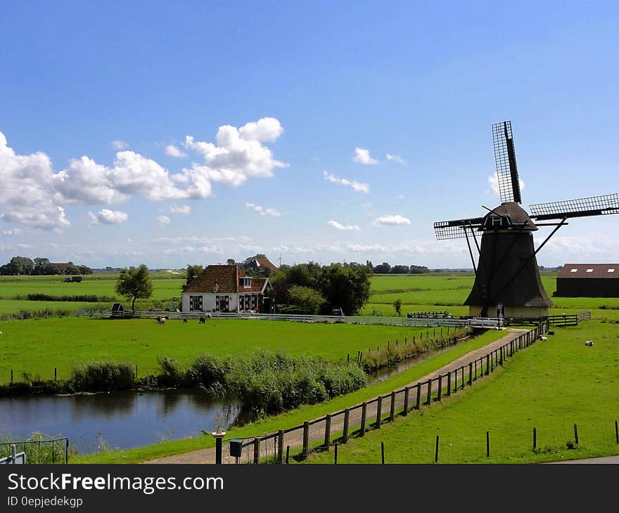 Windmill next to house in green field on sunny day against blue skies. Windmill next to house in green field on sunny day against blue skies.