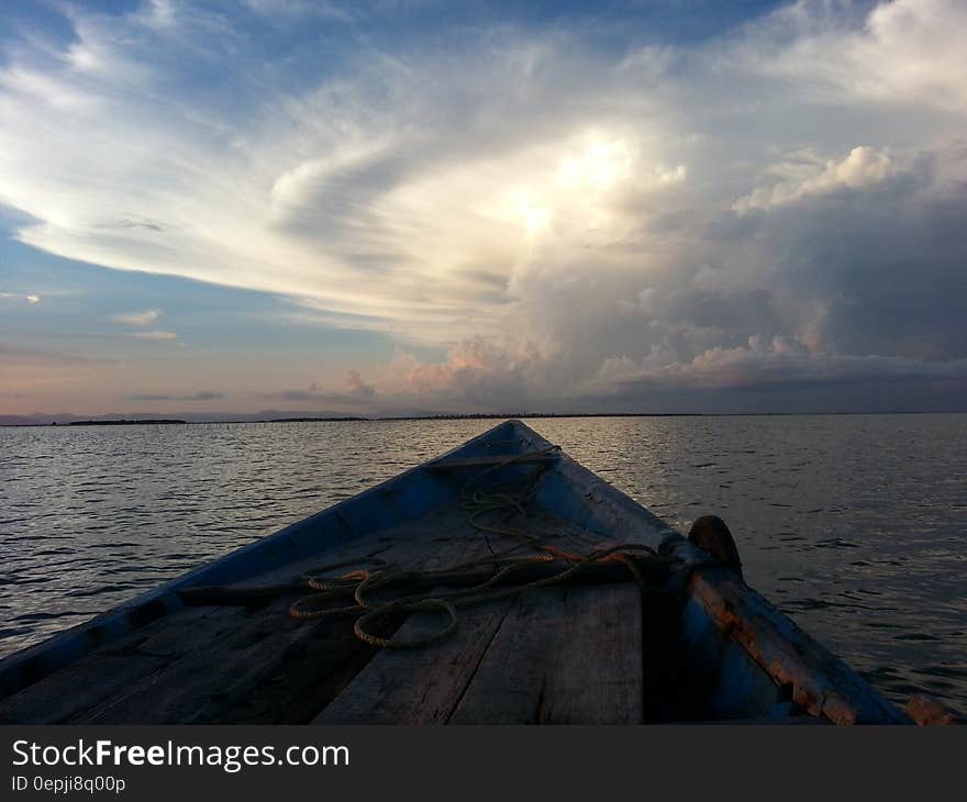 Blue Rowboat on Water Under White Clouds during Daytime