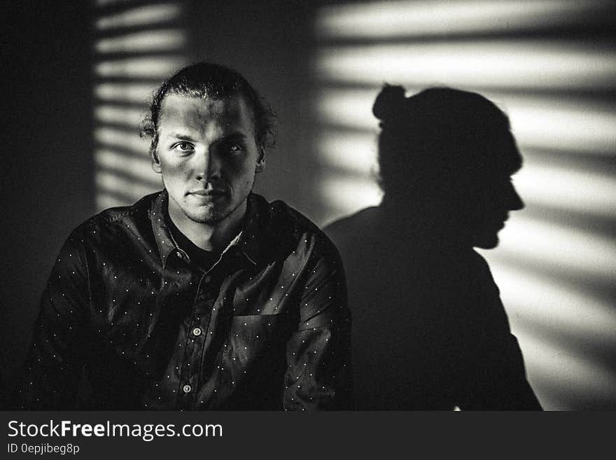 Studio portrait of man next to sunny window with shades in black and white. Studio portrait of man next to sunny window with shades in black and white.