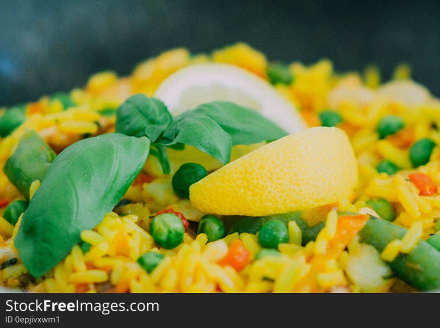 A dish of rice with peas, peppers, basil and a lemon wedge on top. A dish of rice with peas, peppers, basil and a lemon wedge on top.