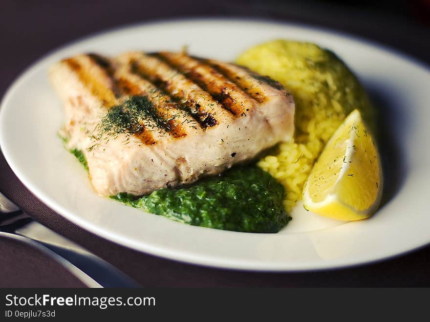 White china plate with grilled salmon, seasoned rice and vegetables with wedge of lemon. White china plate with grilled salmon, seasoned rice and vegetables with wedge of lemon.