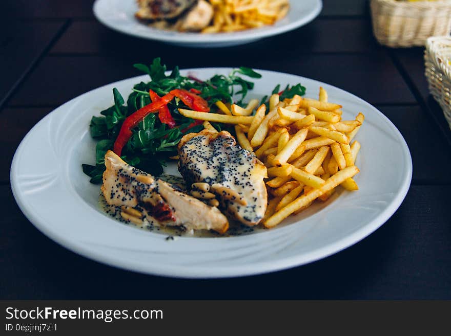 White china plate with roasted chicken and chips or french fries with green salad. White china plate with roasted chicken and chips or french fries with green salad.